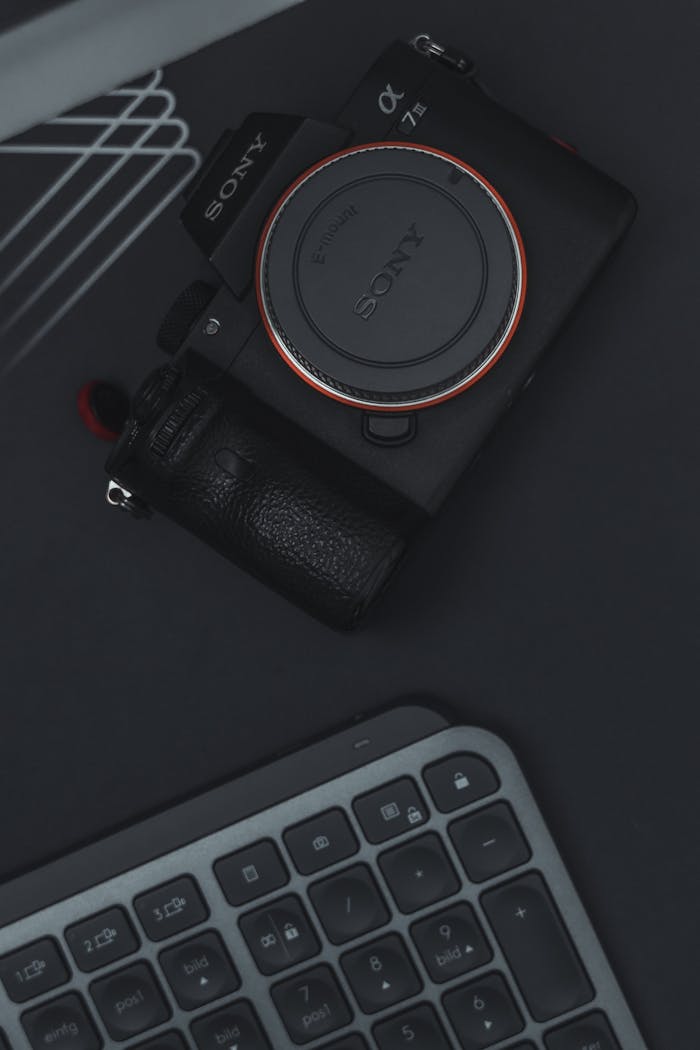 Flat lay of a camera and keyboard on a dark surface, emphasizing technology and modern design.